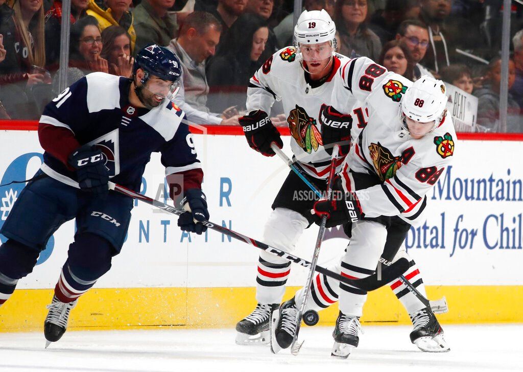 Colorado Avalanche center Nazem Kadri, left, tries to steal the puck from Chicago Blackhawks right wing Patrick Kane as center Jonathan Toews trails the play during the second period of an NHL hockey game Saturday, Dec. 21, 2019, in Denver. (AP Photo/Davi
