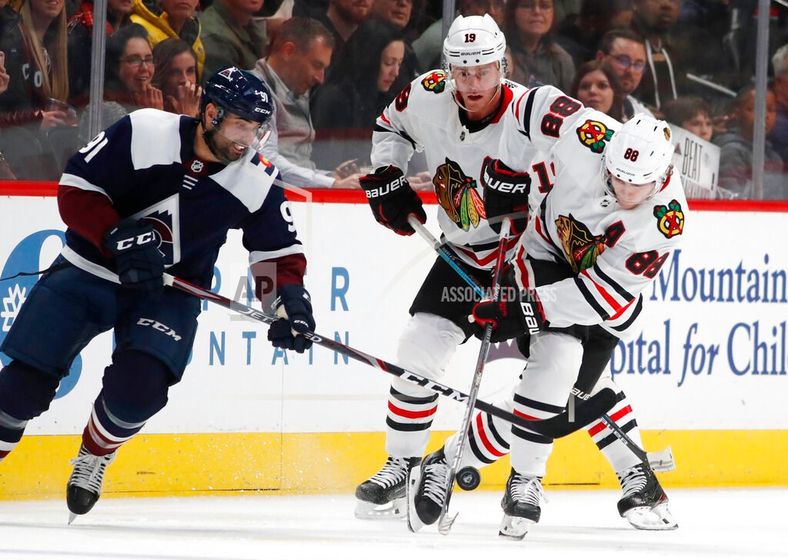 Colorado Avalanche center Nazem Kadri, left, tries to steal the puck from Chicago Blackhawks right wing Patrick Kane as center Jonathan Toews trails the play during the second period of an NHL hockey game Saturday, Dec. 21, 2019, in Denver. (AP Photo/Davi