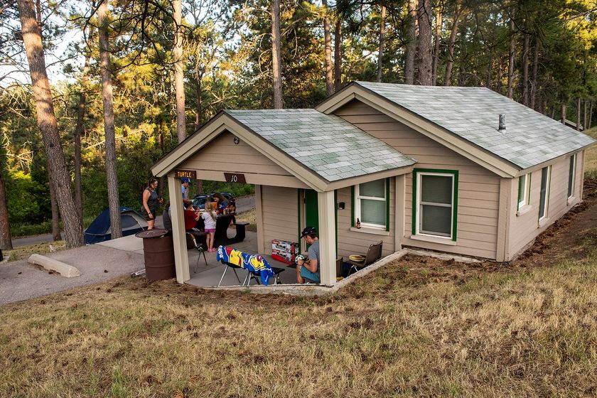 A family gathers at the "Turtle," one of the Chadron State Park's 16 rustic cabins that were built by the Civilian Conservation Corps in the 1930s. In addition to interior improvements, the cabins have been getting new tan siding.