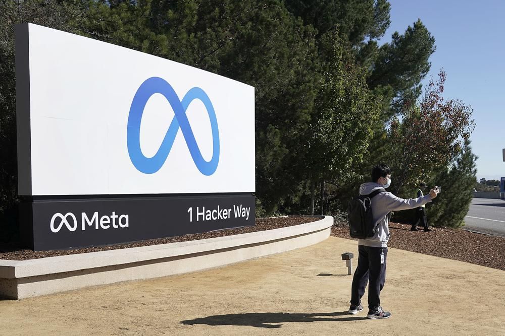 A Facebook employee take a selfie in front the company's new name and logo outside its headquarters in Menlo Park, Calif., Thursday, Oct. 28, 2021, after announcing that it is changing its name to Meta Platforms Inc.